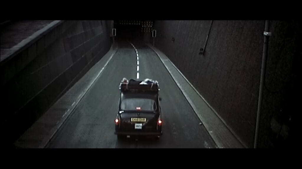 A lone black London cab driving down into an empty, shadowy road tunnel in 28 Days Later.
