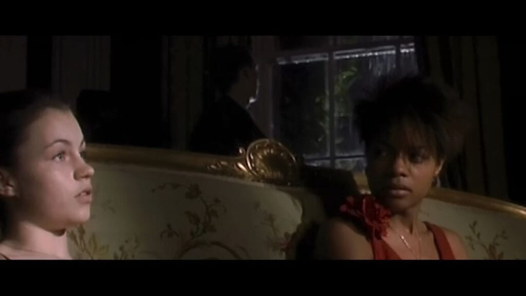 Megan Burns as Hannah and Naomie Harris as Selena sitting on an ornate sofa looking tense and alert in 28 Days Later.
