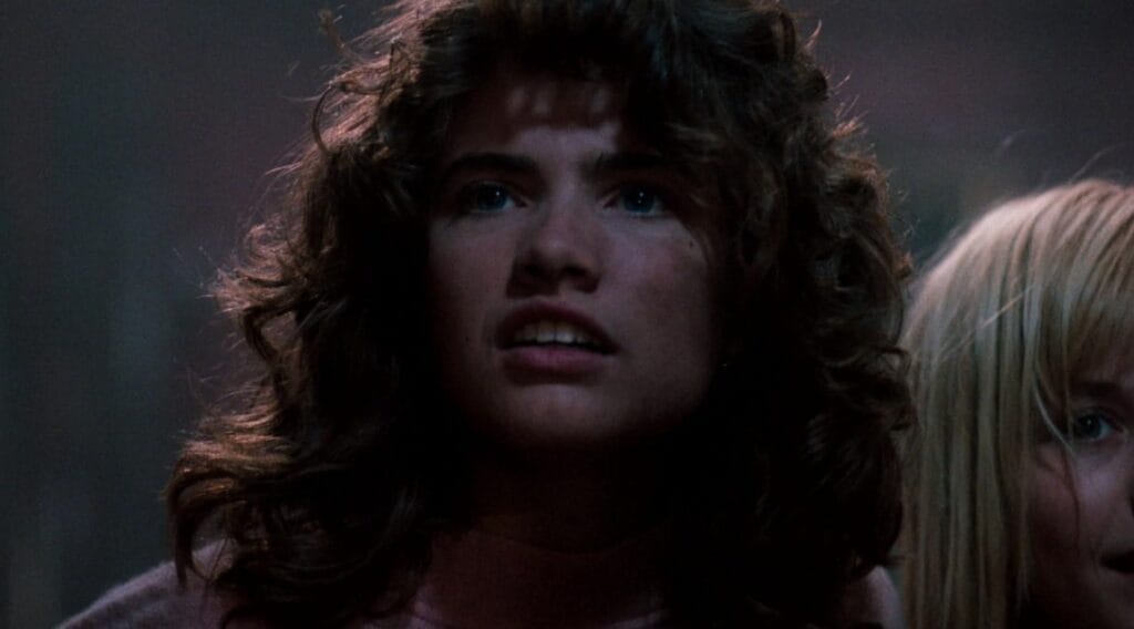Close-up of a wide-eyed Nancy Thompson with dark curly hair looking upward in fear in A Nightmare on Elm Street 3: Dream Warriors.