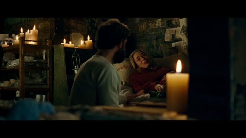 Lee comforting Evelyn as she lies resting in a candlelit underground shelter in A Quiet Place.
