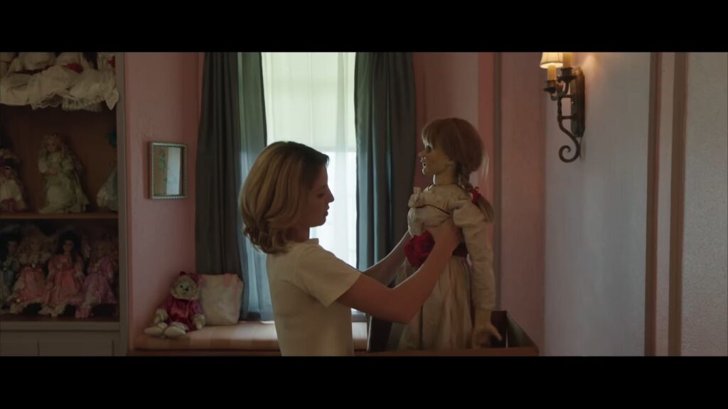Annabelle Wallis as Mia holding the vintage Annabelle doll upright out of a box in Annabelle.
