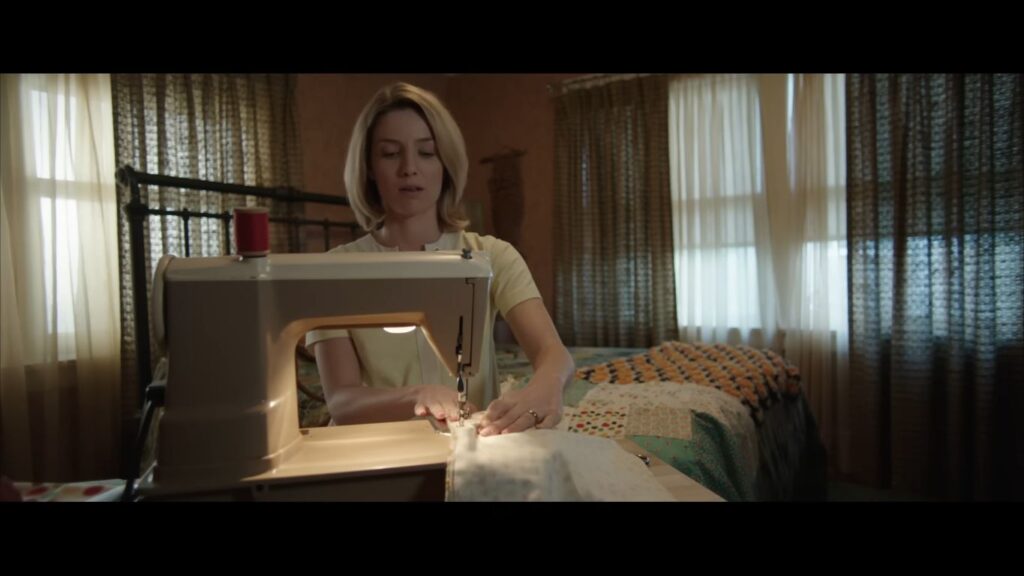 Annabelle Wallis as Mia concentrating while using a sewing machine in a bedroom in Annabelle.