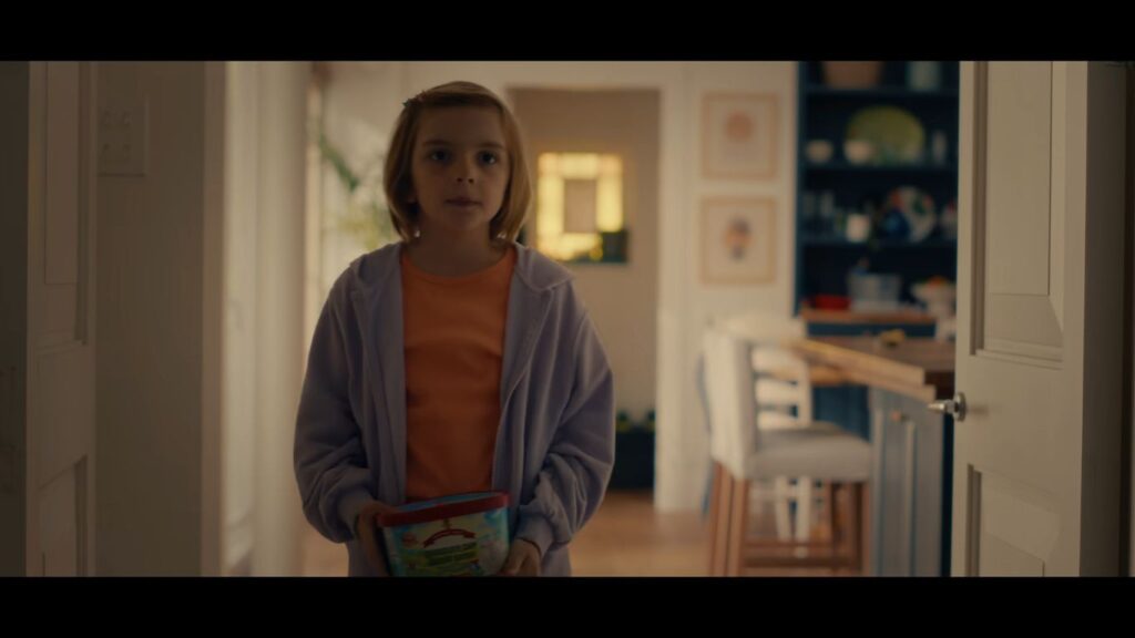 Arabella Olivia Clark as young Bela holding a container indoors in Other Mommy.