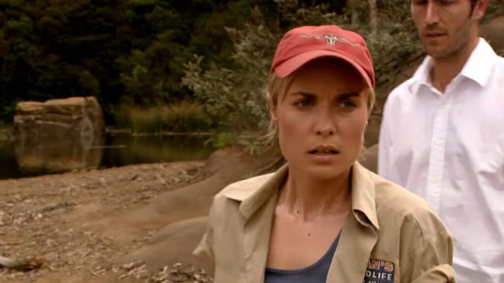 Radha Mitchell as tour guide Kate looking anxious and distressed on a riverbank in Rogue.