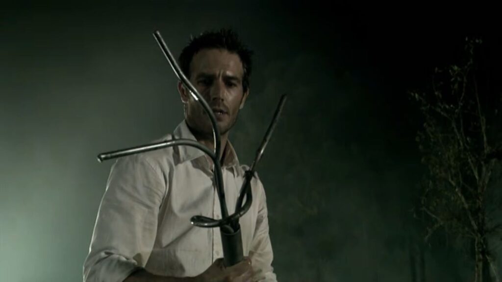 Michael Vartan holding a makeshift spear constructed from bent metal rods in Rogue.