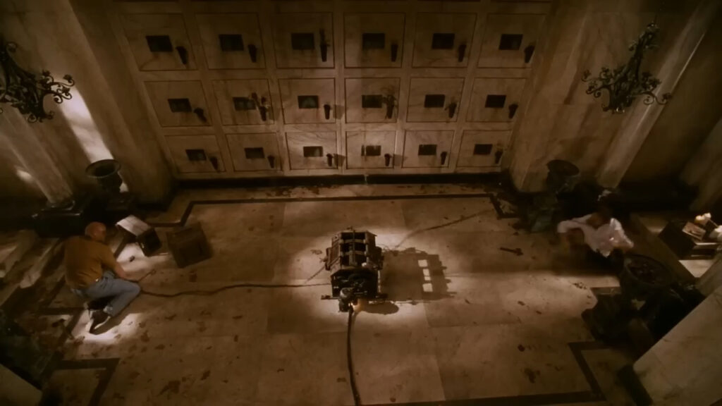 An overhead shot of a trap in a room with a tiled floor and lockers lining the wall in Saw IV.