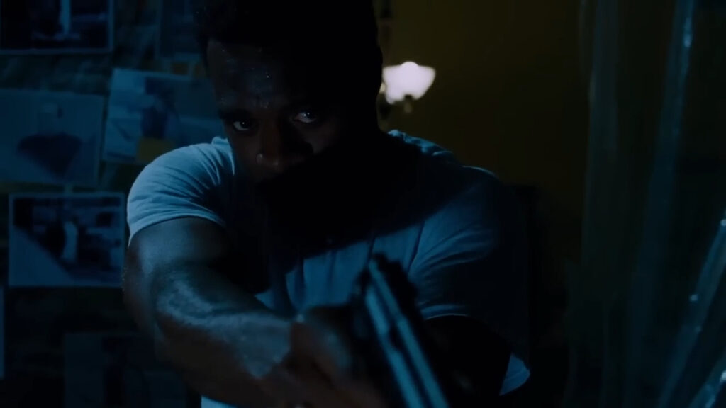 Lyriq Bent as SWAT Commander Rigg aiming a gun in a dimly lit room in Saw IV.