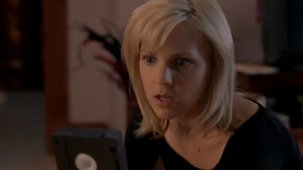 Anna Faris as Cindy looking shocked while examining a mysterious VHS tape in Scary Movie 3.