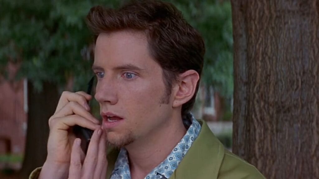 Jamie Kennedy as Randy Meeks speaking nervously into a mobile phone next to a tree in Scream 2.