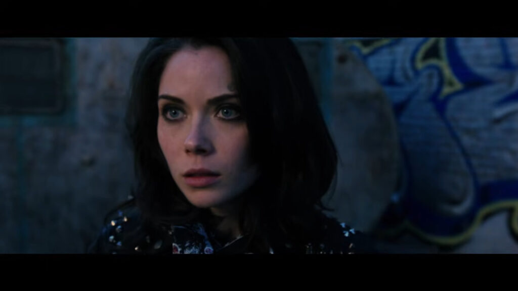 Grace Phipps as Alice wearing a studded leather jacket and looking intense in the alleyway during the The Weak and the Wicked segment of Tales of Halloween.
