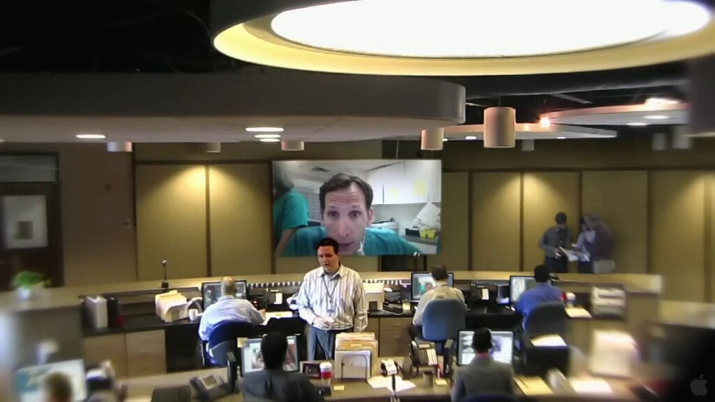 A government control room with multiple monitors displaying a video call from a doctor in The Bay.