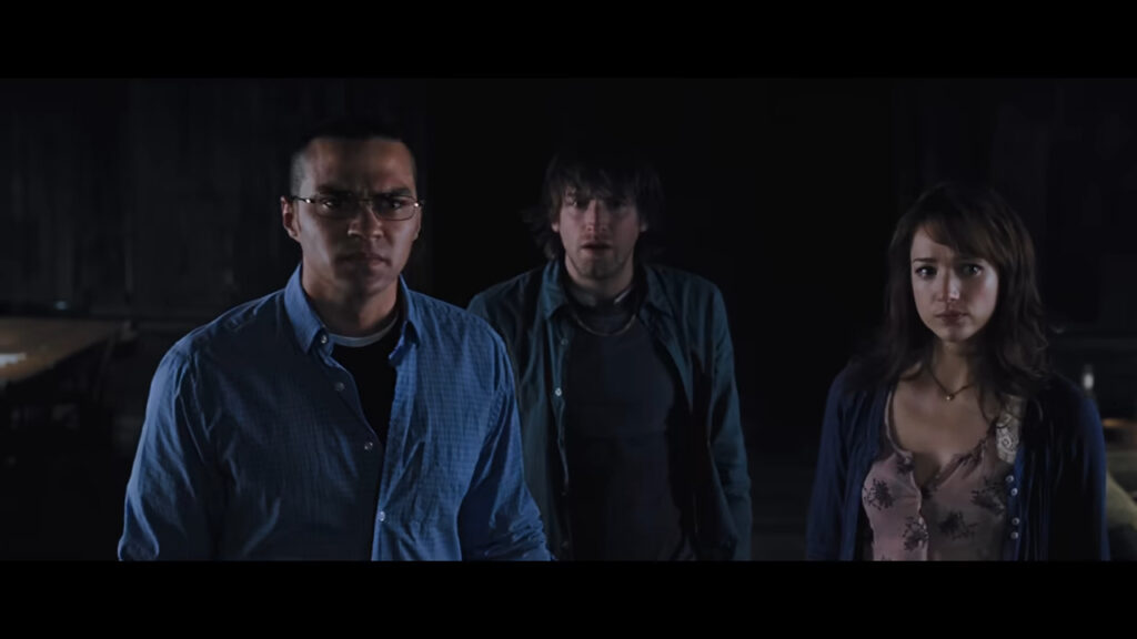 Holden, Marty, and Dana staring forward in shock and confusion inside the cabin in The Cabin in the Woods.