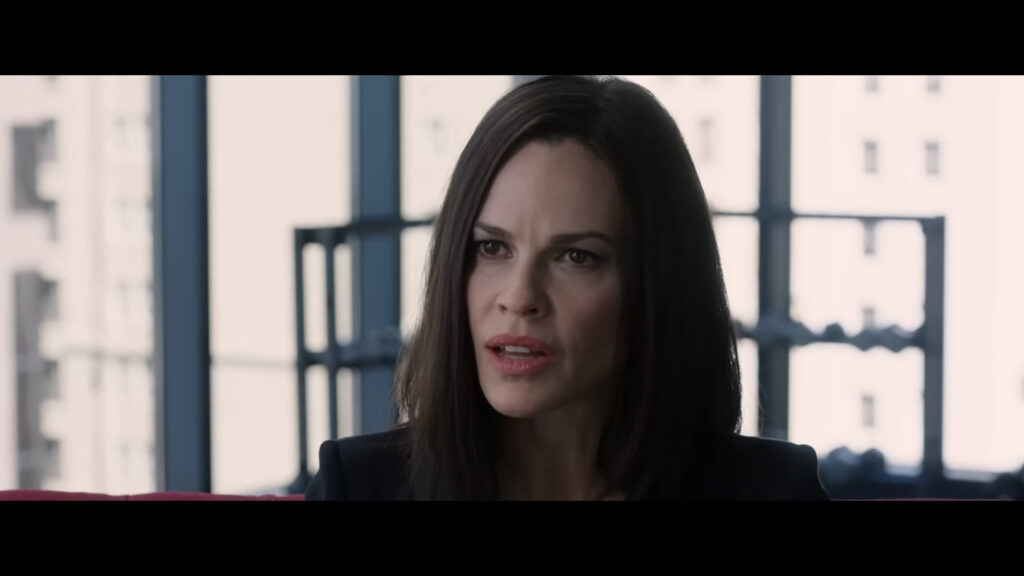 Hilary Swank as Athena Stone speaking sternly during a meeting in The Hunt.