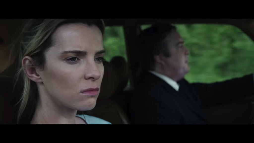 Betty Gilpin as Crystal looking grim and observant in the passenger seat of a car in The Hunt.