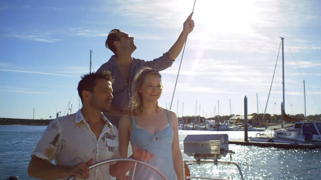Three friends enjoying a sunny day together on a sailboat in The Reef.