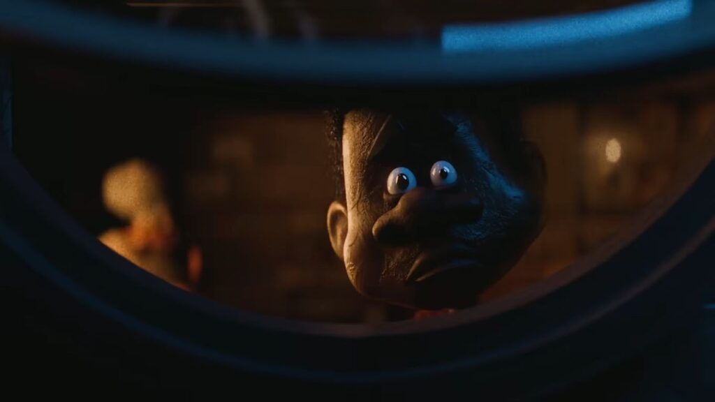 A stop-motion puppet with wide eyes looking intently through a circular frame in V/H/S/Mixtape.