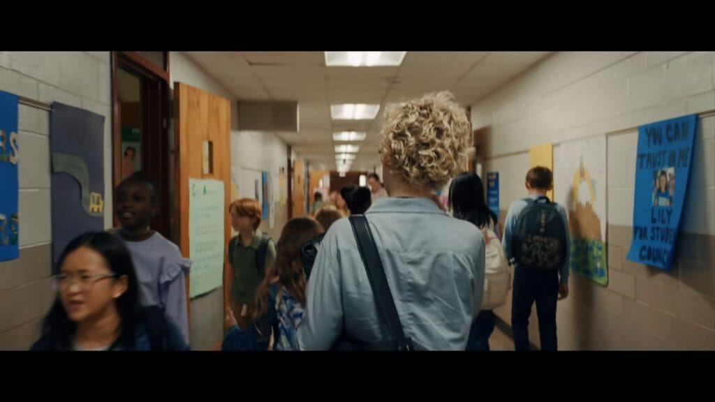 Julia Garner as Justine walking down a bustling, crowded elementary school hallway in Weapons.