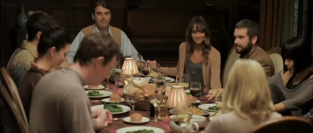The Davison family gathered around a large formal dining table during dinner in You're Next.